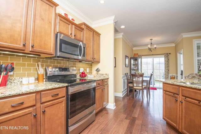 kitchen featuring brown cabinetry, dark wood finished floors, appliances with stainless steel finishes, backsplash, and a chandelier