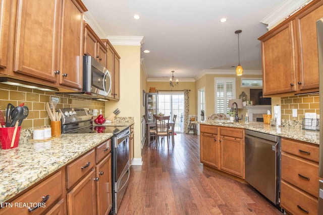 kitchen with brown cabinetry, a peninsula, stainless steel appliances, dark wood-type flooring, and crown molding