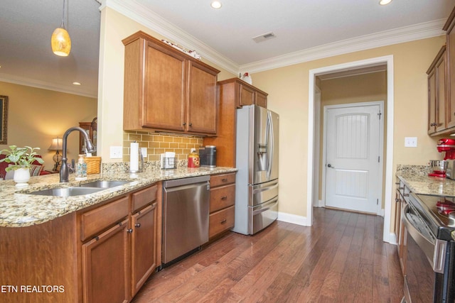 kitchen with brown cabinets, dark wood-type flooring, ornamental molding, a sink, and appliances with stainless steel finishes