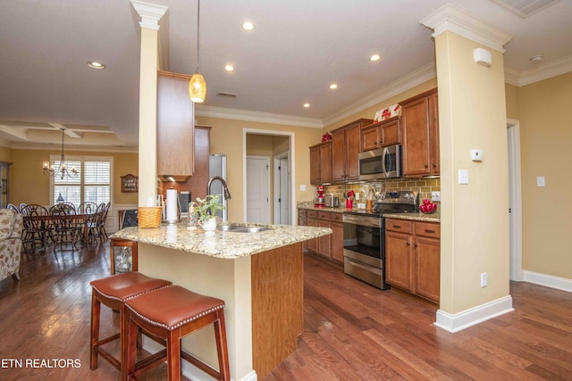 kitchen with a sink, a kitchen bar, brown cabinets, and appliances with stainless steel finishes