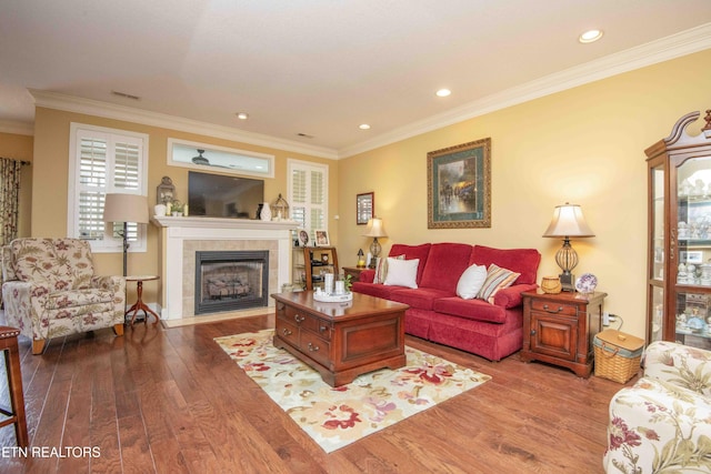 living room with wood finished floors, visible vents, a fireplace, recessed lighting, and ornamental molding