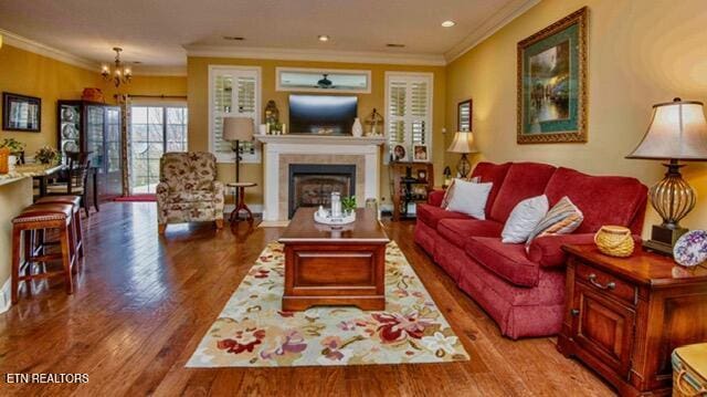 living area featuring a fireplace, wood finished floors, crown molding, and recessed lighting