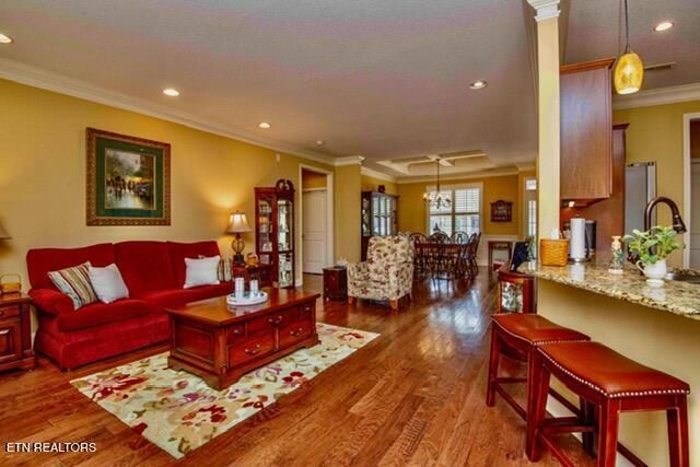 living room featuring wood finished floors, recessed lighting, and ornamental molding