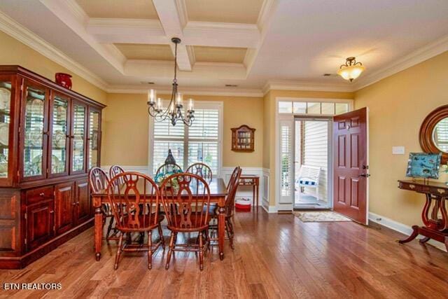 dining room with coffered ceiling, wood finished floors, a chandelier, and ornamental molding