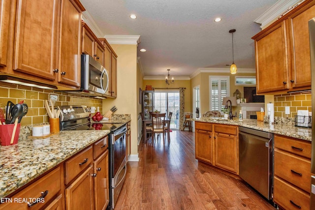 kitchen with brown cabinetry, appliances with stainless steel finishes, and ornamental molding