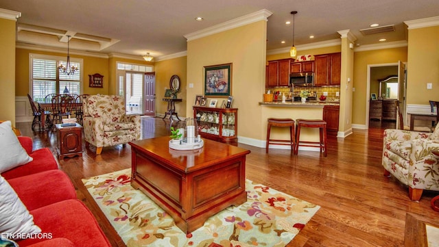 living room featuring crown molding, wood finished floors, a notable chandelier, visible vents, and recessed lighting