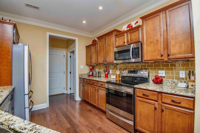 kitchen featuring stainless steel appliances, visible vents, brown cabinetry, dark wood-type flooring, and ornamental molding