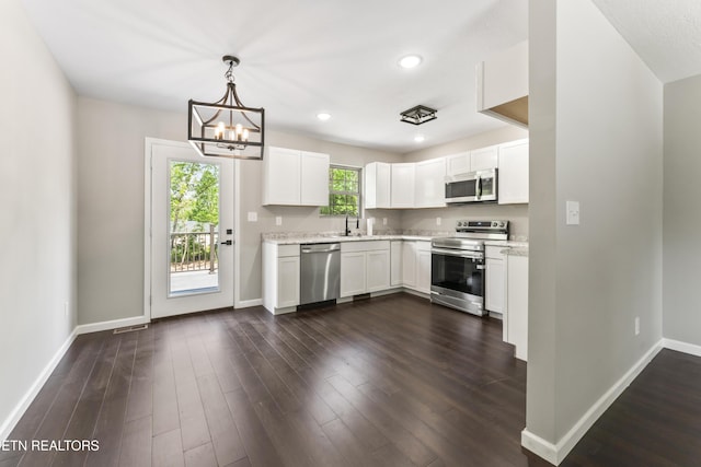 kitchen with baseboards, stainless steel appliances, white cabinetry, and a chandelier