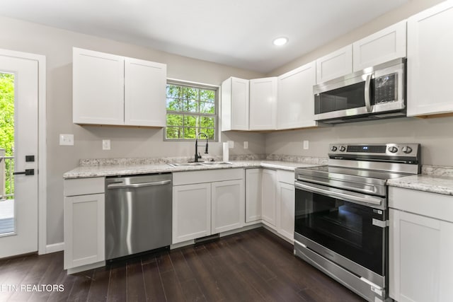 kitchen with a sink, white cabinets, stainless steel appliances, and dark wood-style floors