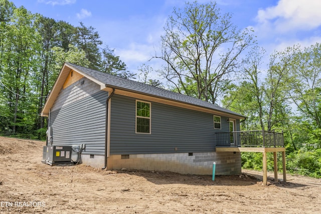 view of side of property with crawl space, central AC unit, a shingled roof, and a wooden deck
