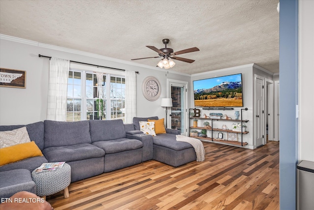 living room with a textured ceiling, crown molding, a ceiling fan, and wood finished floors