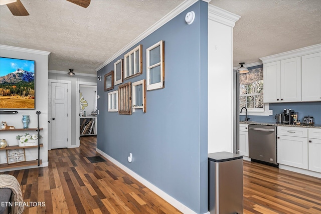 hallway with visible vents, ornamental molding, a textured ceiling, dark wood finished floors, and baseboards