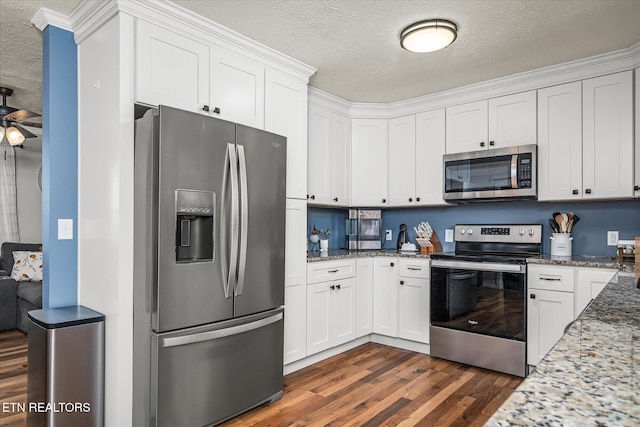 kitchen with dark wood-type flooring, light stone countertops, appliances with stainless steel finishes, white cabinets, and a textured ceiling