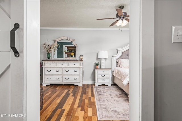 unfurnished bedroom with a textured ceiling, crown molding, baseboards, and wood finished floors