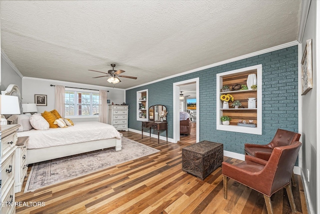 bedroom with brick wall, a textured ceiling, crown molding, and wood finished floors