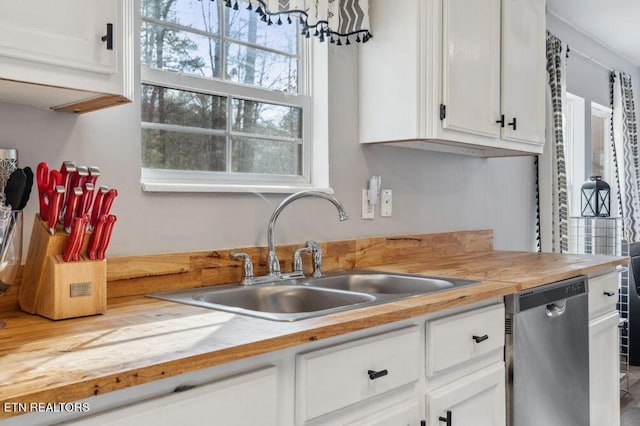 kitchen with a sink, white cabinets, wooden counters, and stainless steel dishwasher