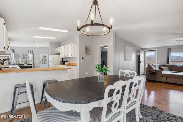 dining room featuring vaulted ceiling, an inviting chandelier, and dark wood-style flooring