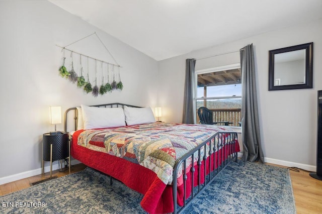 bedroom featuring visible vents, baseboards, wood finished floors, and vaulted ceiling