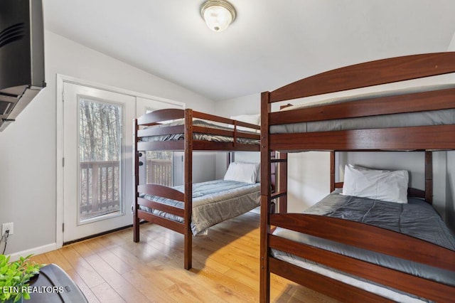 bedroom featuring hardwood / wood-style floors, lofted ceiling, and baseboards