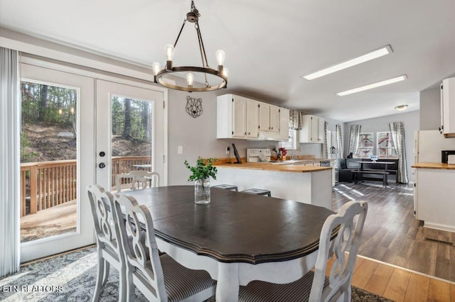 dining area with an inviting chandelier, wood finished floors, visible vents, and lofted ceiling