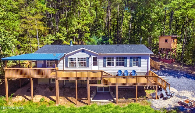 back of house with a wooded view and a wooden deck