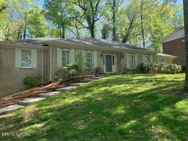 single story home featuring brick siding and a front yard