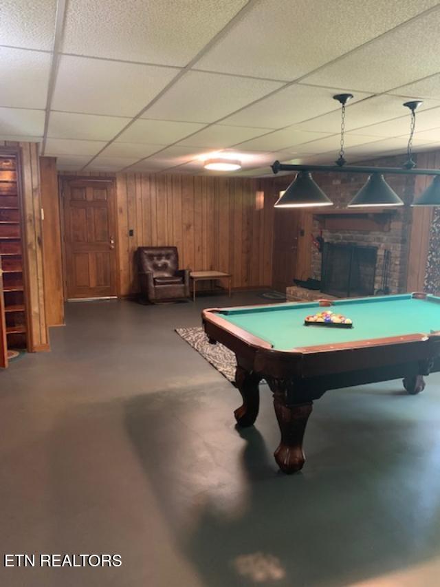 playroom featuring a paneled ceiling, concrete floors, wood walls, and billiards