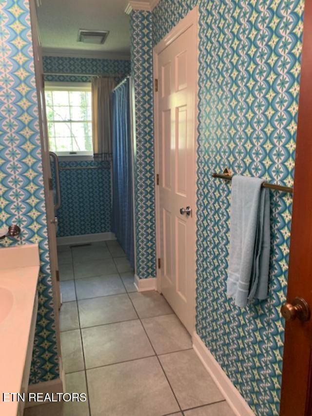 bathroom featuring tile patterned floors, visible vents, baseboards, and wallpapered walls