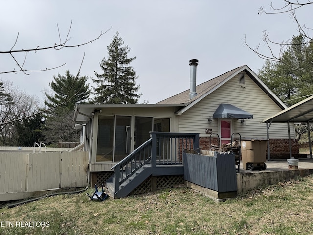 rear view of property featuring fence, a wooden deck, a lawn, a sunroom, and a gate