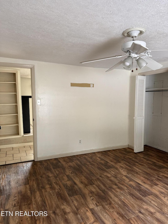 unfurnished bedroom featuring baseboards, a textured ceiling, and dark wood finished floors