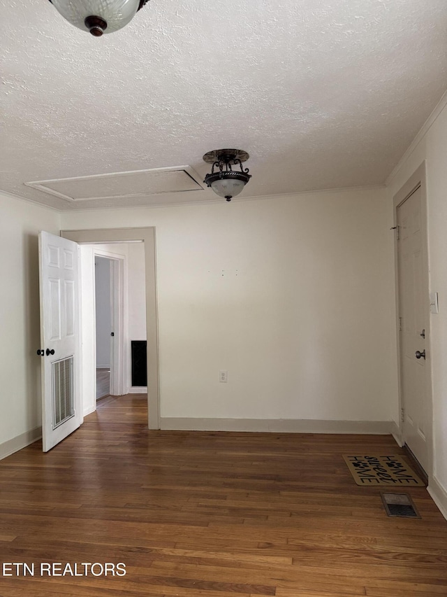 spare room featuring baseboards, wood finished floors, visible vents, and a textured ceiling