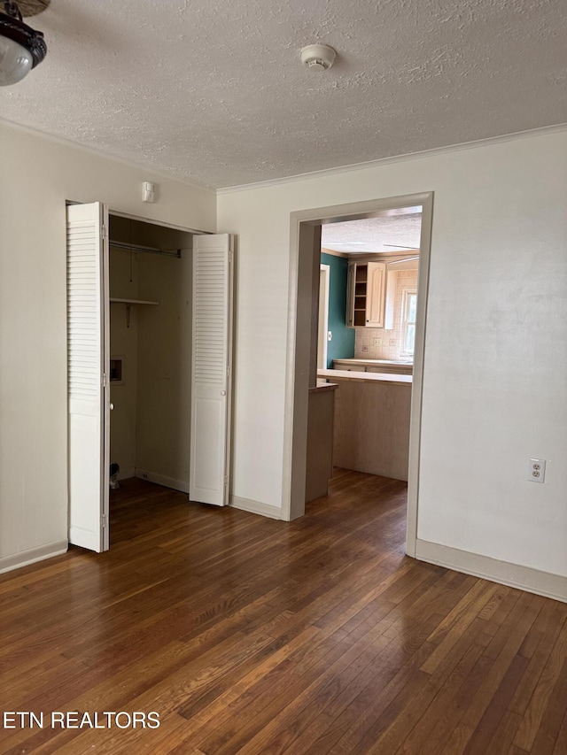 interior space featuring dark wood finished floors, baseboards, a textured ceiling, and a closet