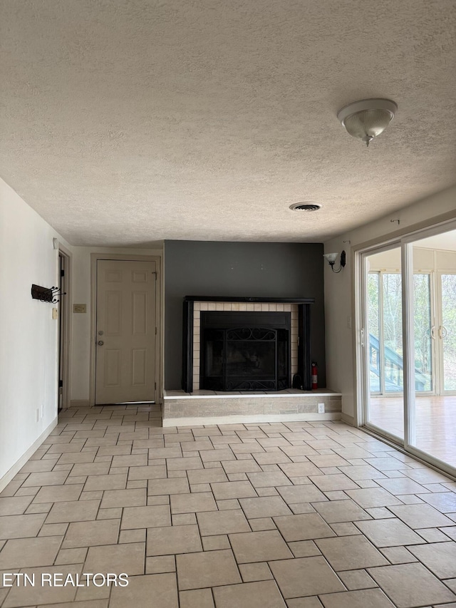 unfurnished living room featuring a fireplace, a textured ceiling, and baseboards