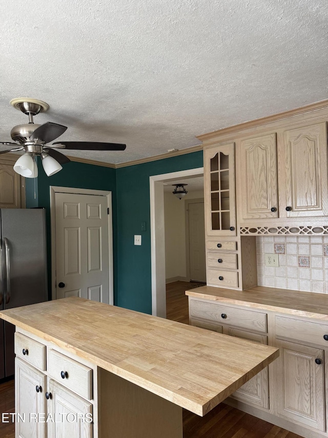 kitchen with backsplash, glass insert cabinets, butcher block countertops, freestanding refrigerator, and a ceiling fan