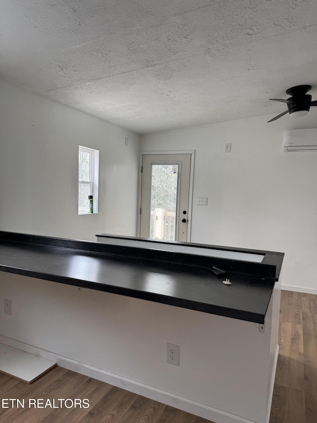 details with a textured ceiling, wood finished floors, and a wall mounted AC