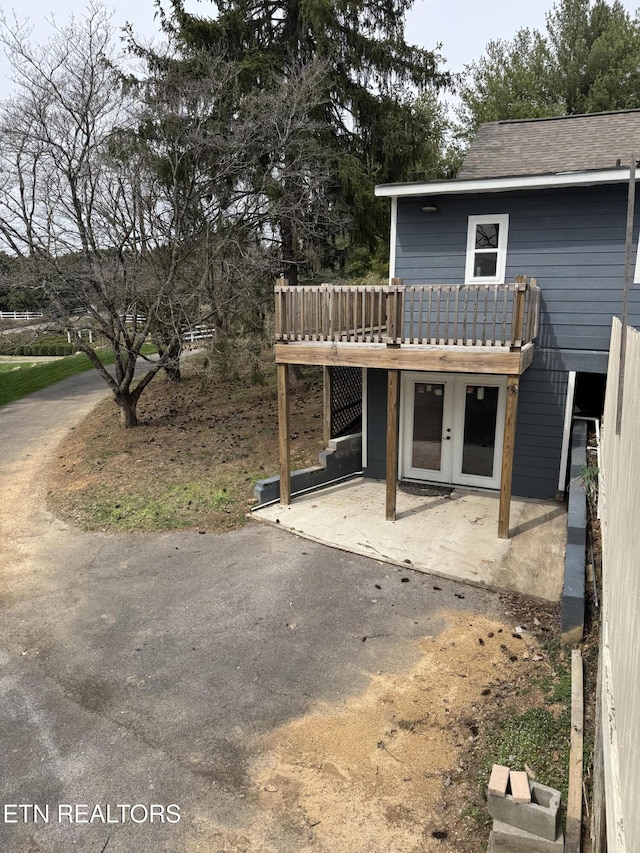 rear view of property with a wooden deck, a patio, and french doors