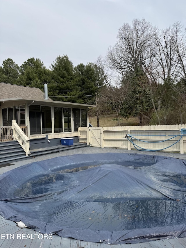 view of swimming pool featuring a fenced in pool, a sunroom, fence, and a gate