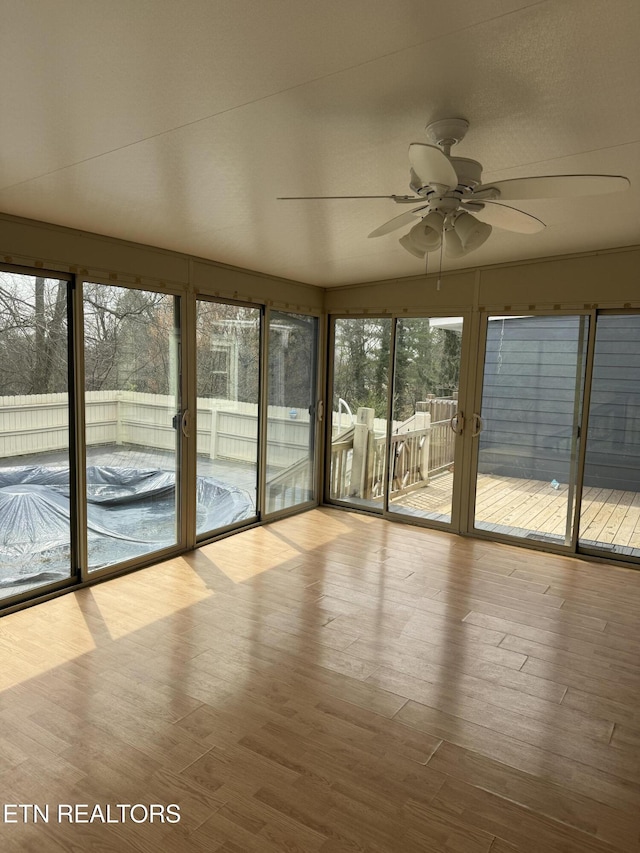 unfurnished sunroom featuring a ceiling fan