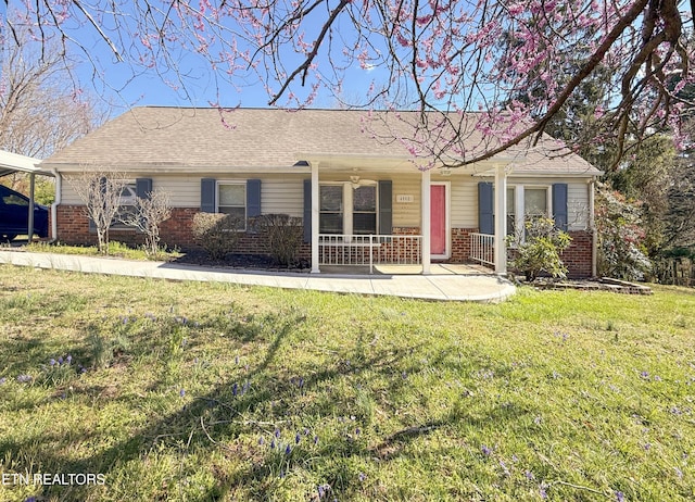 ranch-style house with a shingled roof, a front yard, covered porch, and brick siding