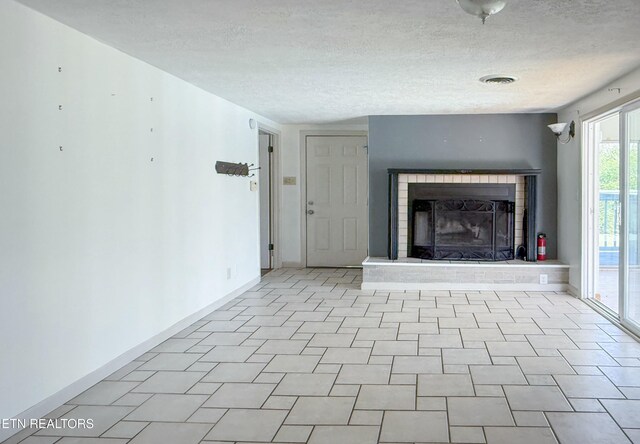 unfurnished living room featuring a textured ceiling, baseboards, a fireplace, and visible vents