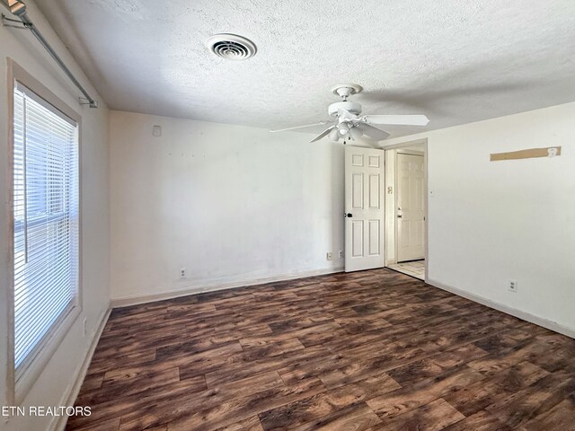 empty room with a textured ceiling, visible vents, a ceiling fan, and wood finished floors