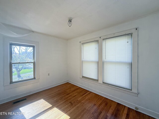 empty room featuring baseboards, visible vents, and wood finished floors