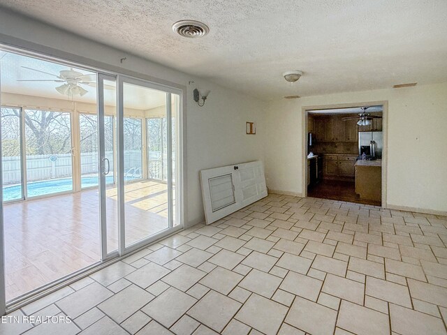 empty room with a textured ceiling, ceiling fan, and visible vents