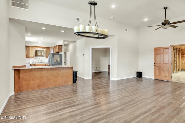 kitchen with visible vents, open floor plan, freestanding refrigerator, wood finished floors, and brown cabinetry