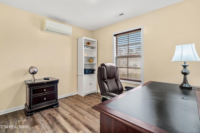 office featuring visible vents, baseboards, a wall unit AC, and wood finished floors