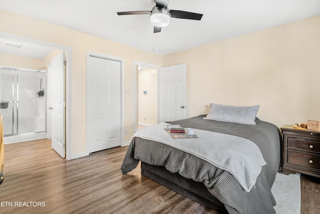 bedroom with ensuite bath, wood finished floors, a closet, baseboards, and ceiling fan