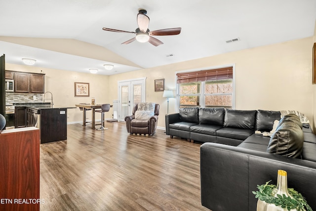 living area with wood finished floors, a ceiling fan, visible vents, lofted ceiling, and french doors