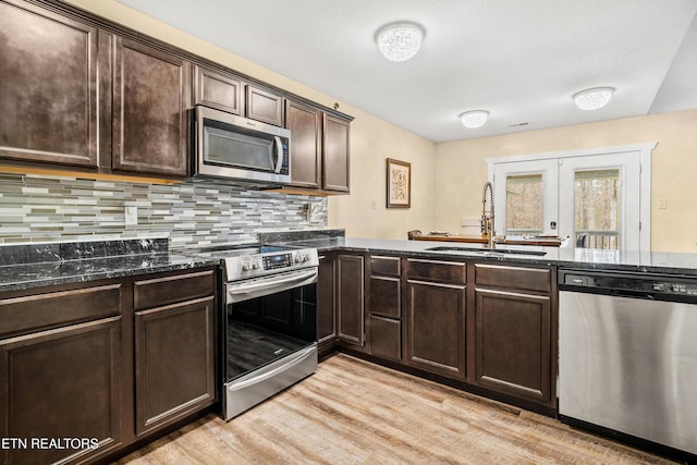 kitchen featuring dark stone counters, a sink, stainless steel appliances, dark brown cabinets, and french doors