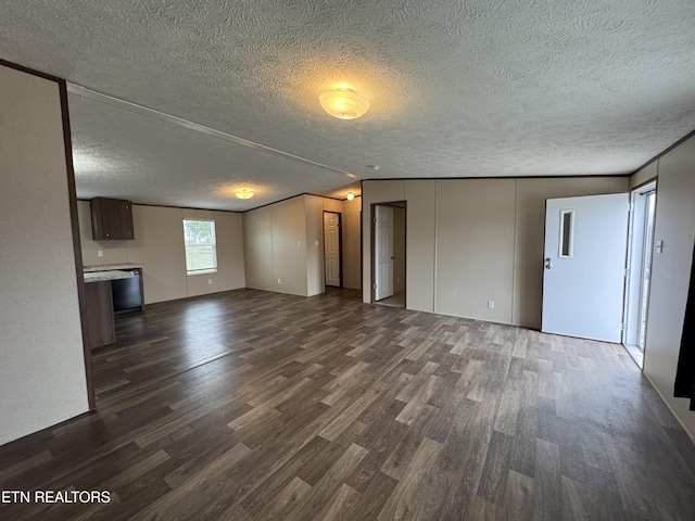 unfurnished living room with a textured ceiling, dark wood-type flooring, and vaulted ceiling