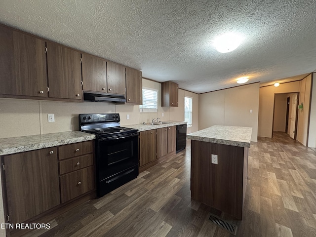 kitchen with under cabinet range hood, visible vents, black appliances, and dark wood-style flooring